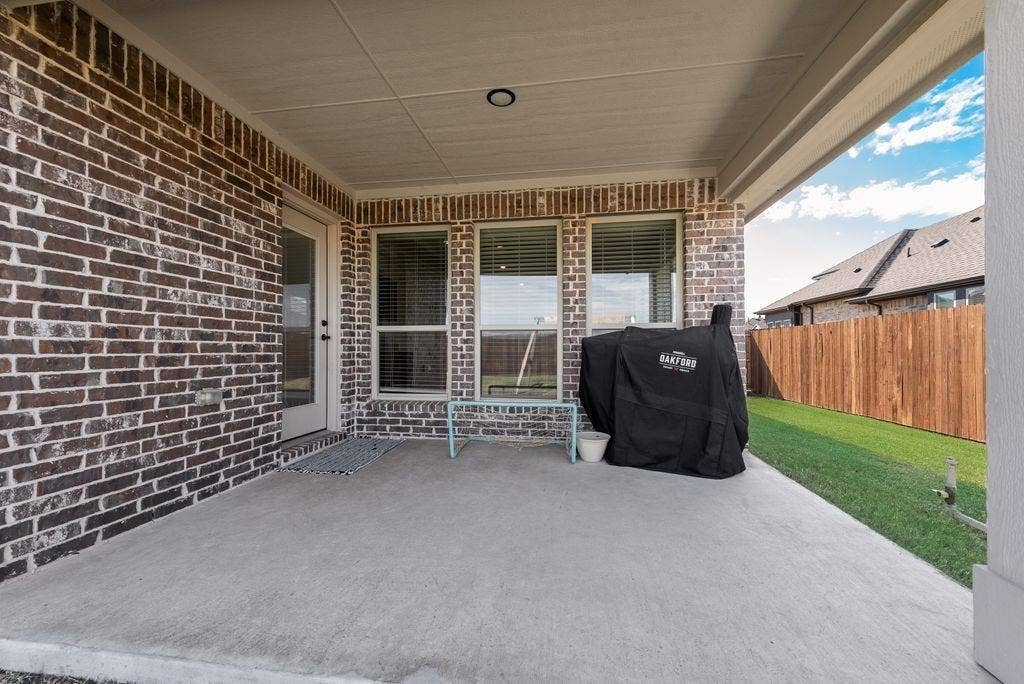 208 Shady Bank Way, Nevada, TX 75173 Covered concrete patio featuring brick exterior walls, multiple windows with blinds, and a fenced backyard