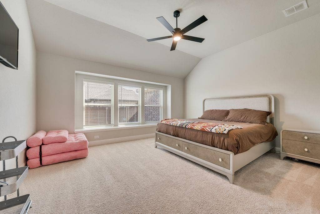 208 Shady Bank Way, Nevada, TX 75173 Vaulted ceiling, neutral wall tones, wall-to-wall carpeting, expansive triple-pane window, and matte black ceiling fan with integrated lighting