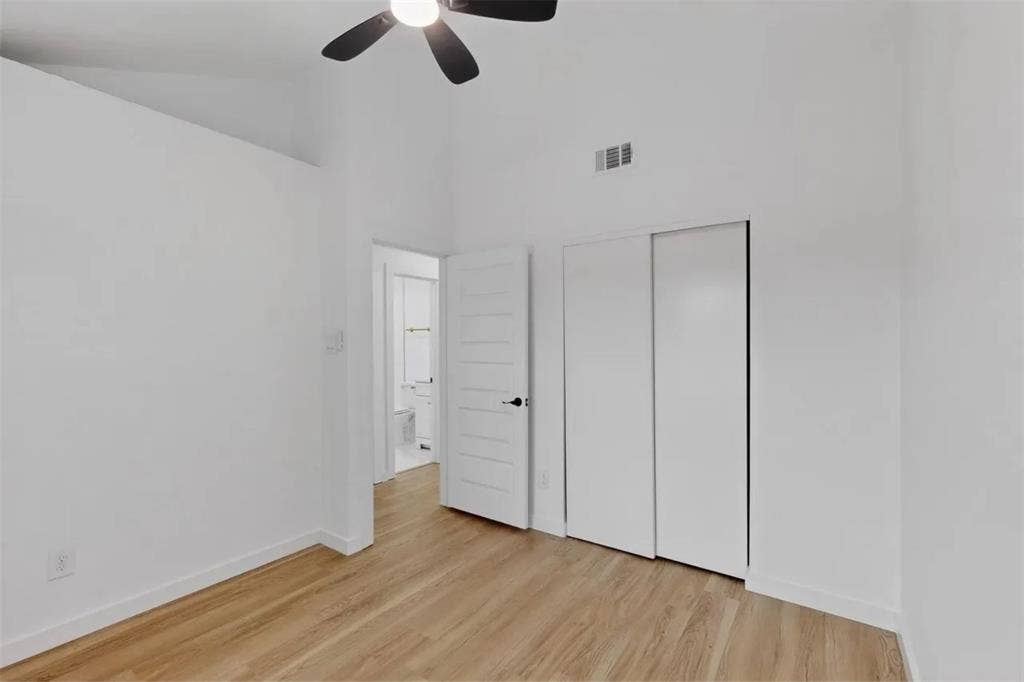 Vaulted ceilings, wood-finish flooring, sliding closet doors, and an attached ceiling fan with integrated lighting