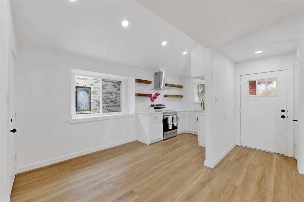 Kitchen featuring white cabinetry, wood-finish flooring, recessed lighting, stainless steel appliances, and floating wood shelving