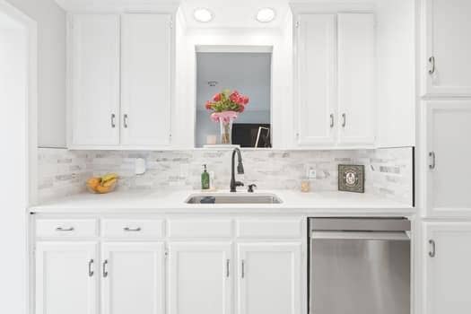 Kitchen featuring white cabinetry, stone-style tile backsplash, stainless steel dishwasher, matte black faucet, and recessed lighting