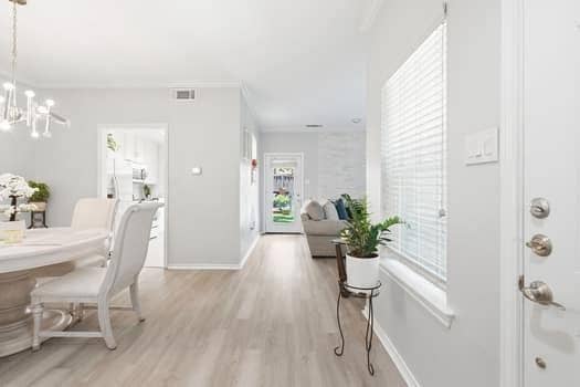 Interior space featuring wood-finish flooring, a multi-light chandelier, horizontal window blinds, and a glass-paneled entry door
