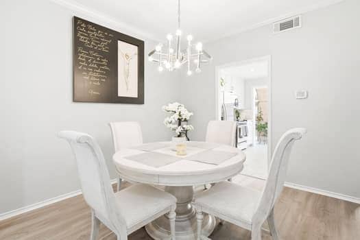 Multi-arm metallic chandelier featuring exposed bulbs, wood-finish flooring, and crown molding