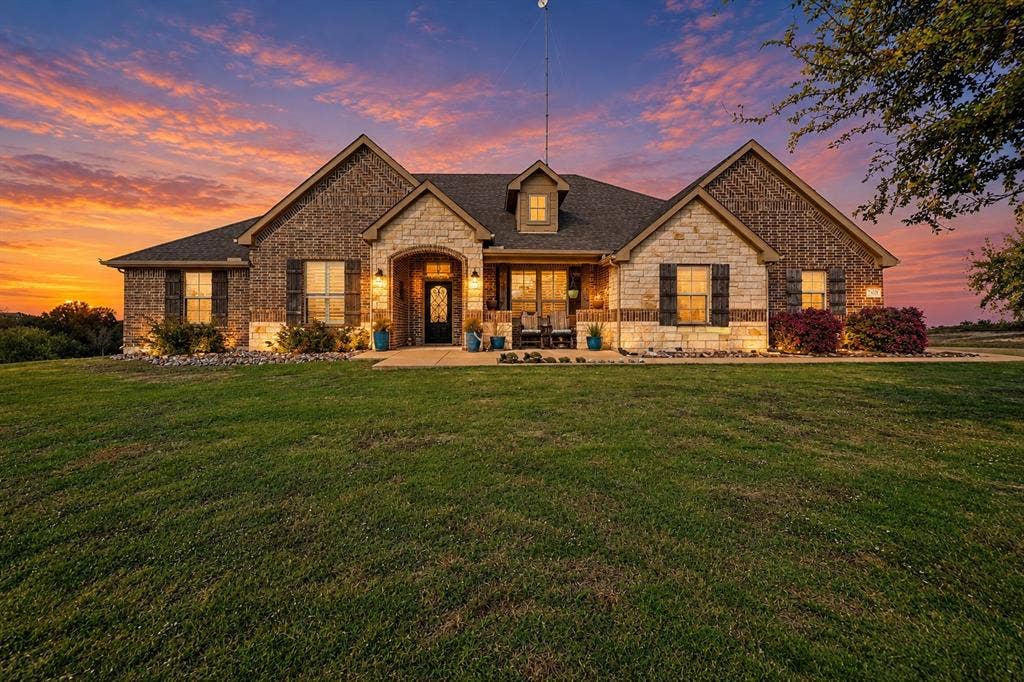 2828 Luke Drive, Farmersville, TX 75442 Single-story residence featuring a mixed-material facade of brick and cut stone, arched entryway, shingle roof, and dark decorative shutters