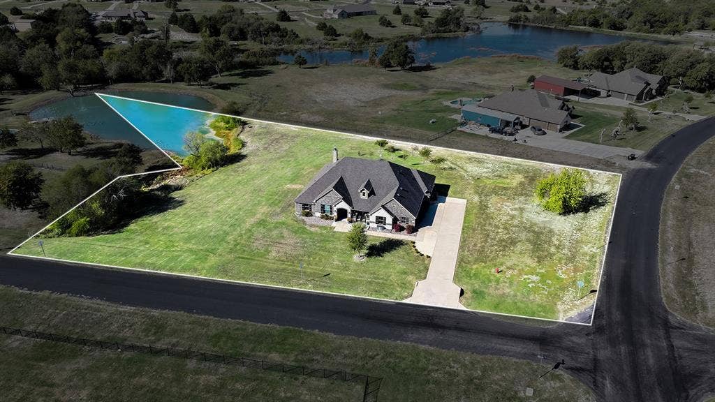 2828 Luke Drive, Farmersville, TX 75442 Aerial perspective of a detached residence featuring a multi-pitched roof, concrete driveway, and expansive acreage including a pond
