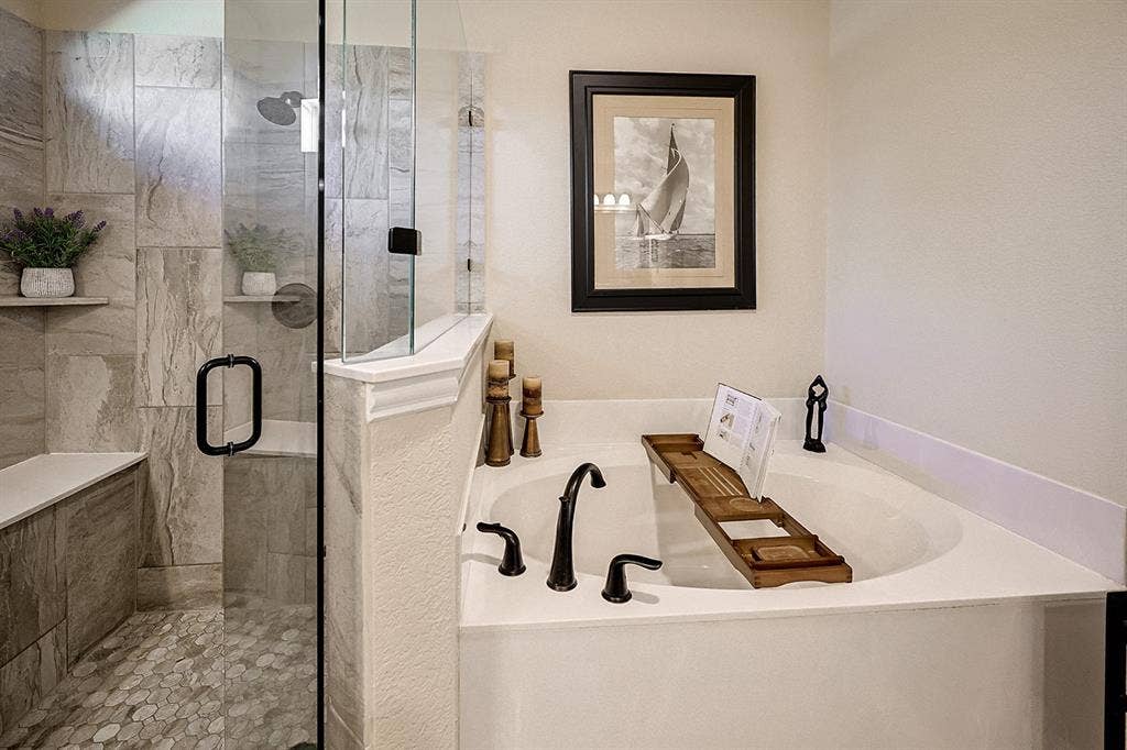 2828 Luke Drive, Farmersville, TX 75442 Soaking tub with a deck-mounted faucet, glass-enclosed shower featuring large-format tile surround, integrated bench seating, and pebble-finish shower floor