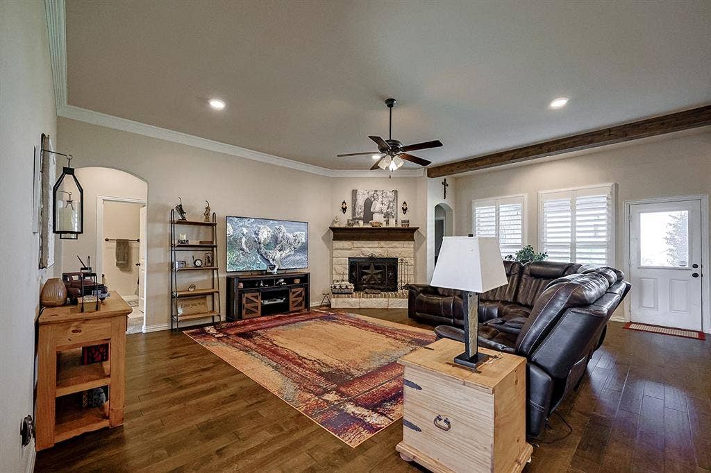 2828 Luke Drive, Farmersville, TX 75442 Living area featuring wood-finish flooring, stone fireplace with a dark wood mantel, recessed lighting, ceiling fan, and plantation shutters