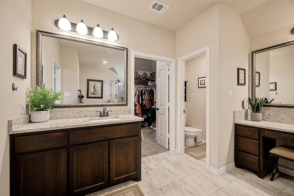 2828 Luke Drive, Farmersville, TX 75442 Bathroom featuring dark-finish wood cabinetry, speckled stone-surface countertops, dual rectangular under-mount sinks, large framed mirrors, and tile flooring