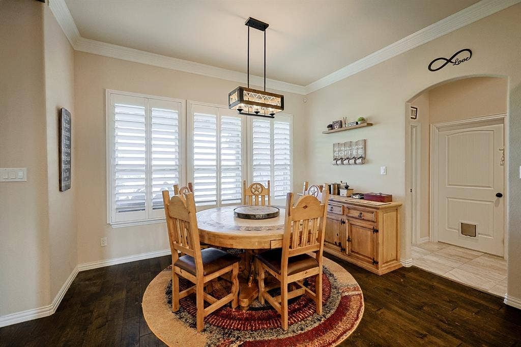 2828 Luke Drive, Farmersville, TX 75442 Dining area featuring wood-finish flooring, plantation shutters, crown molding, and a rectangular multi-light pendant fixture