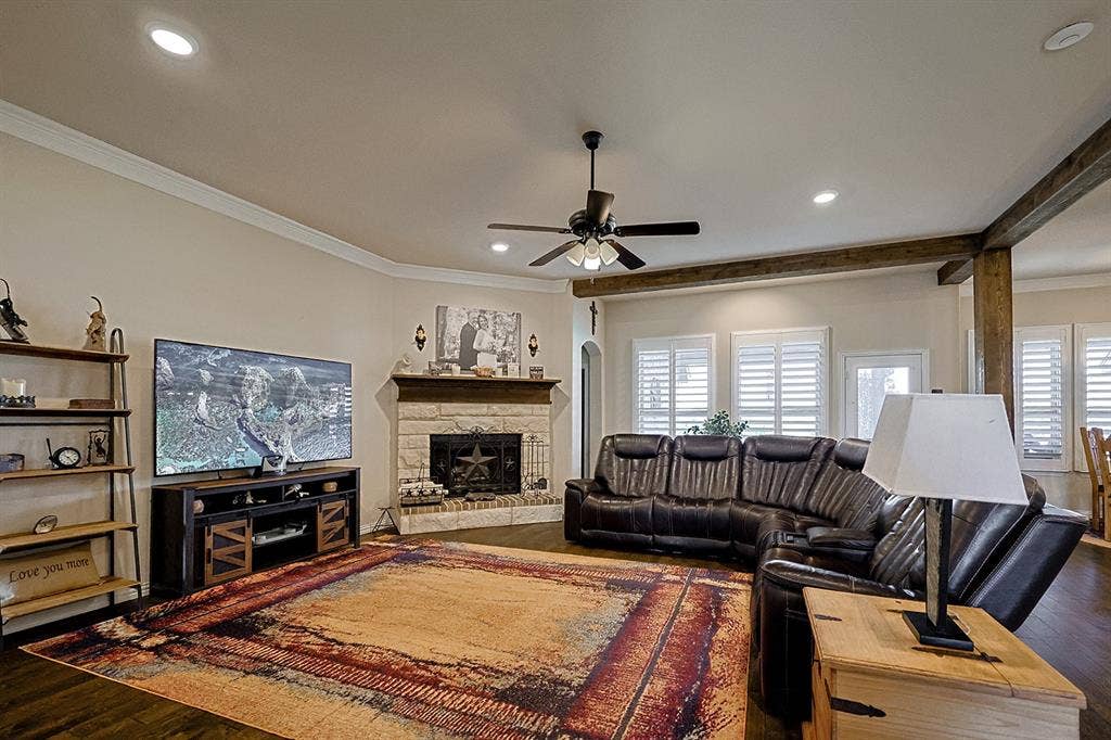 2828 Luke Drive, Farmersville, TX 75442 Living area featuring stone-surround corner fireplace with timber mantel, recessed lighting, ceiling fan, crown molding, and plantation shutters