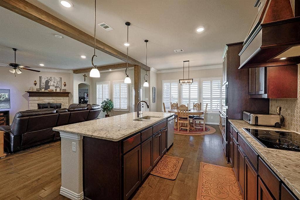 2828 Luke Drive, Farmersville, TX 75442 Stone fireplace with wooden mantel, wood-finish flooring, exposed wooden ceiling beams, recessed lighting, and wooden cabinetry
