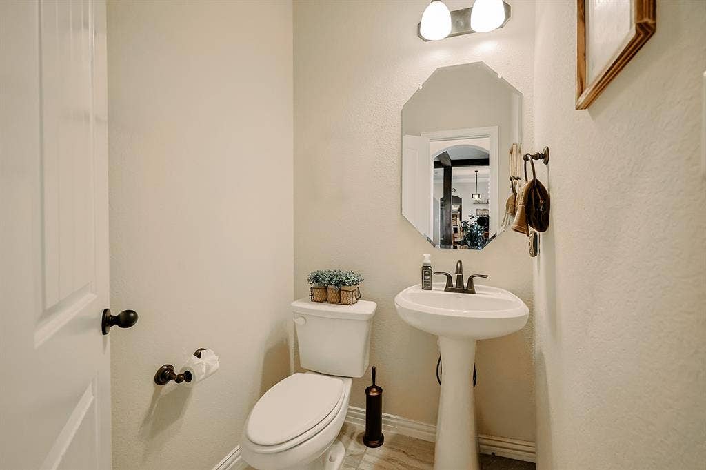2828 Luke Drive, Farmersville, TX 75442 Powder room featuring a porcelain pedestal sink, dual-handle oil-rubbed bronze faucet, octagonal wall mirror, and two-light vanity fixture