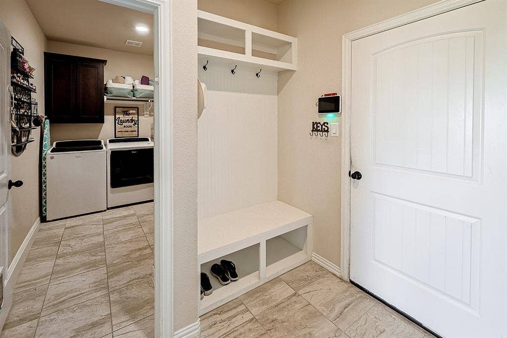 2828 Luke Drive, Farmersville, TX 75442 Mudroom area featuring built-in cabinetry with bench seating and overhead storage, tile flooring, and dark wood-finish wall cabinets