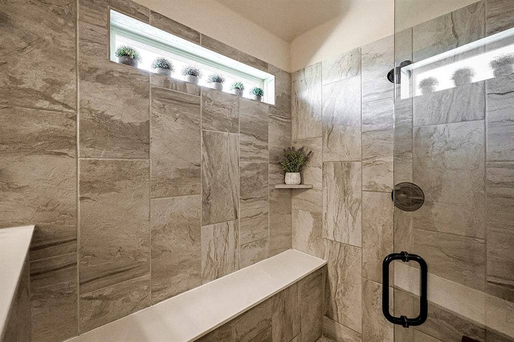 2828 Luke Drive, Farmersville, TX 75442 Walk-in shower featuring floor-to-ceiling stone-pattern tile, a built-in bench, integrated corner shelving, a horizontal transom window, and a frameless glass door with matte black hardware