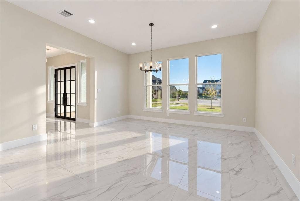 Large format tile flooring, recessed lighting, multi-pane window configuration, and a decorative metal chandelier