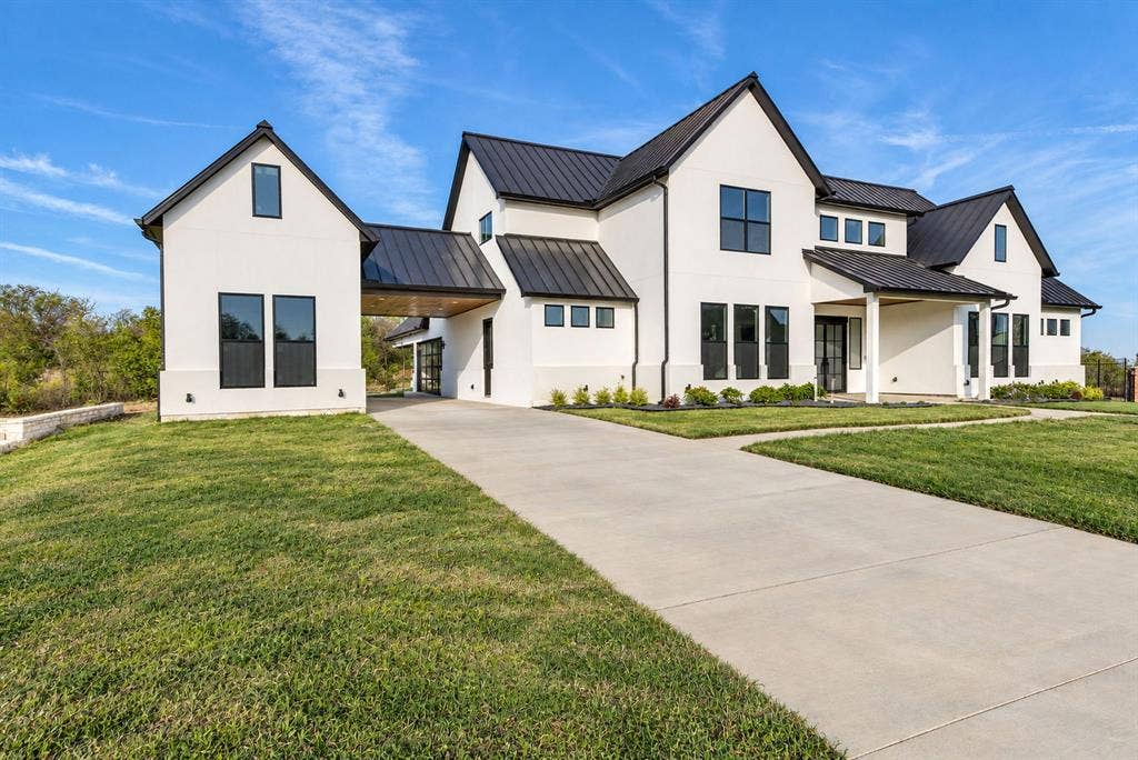 Modern residence featuring a crisp white facade, steep rooflines with metal roofing, multiple gables, and dark-framed windows