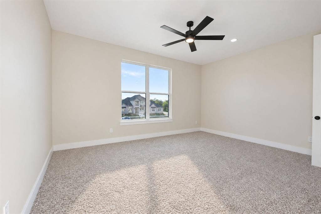 Neutral-toned interior space featuring wall-to-wall carpeting, a multi-pane window, and a matte black ceiling fan with an integrated light fixture