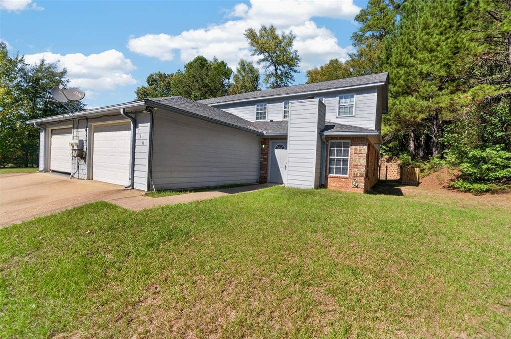 1708 Timber View Drive, Tyler, TX 75703 Two-story exterior featuring gray lap siding, brick masonry detailing, a two-car garage, and an asphalt shingle roof