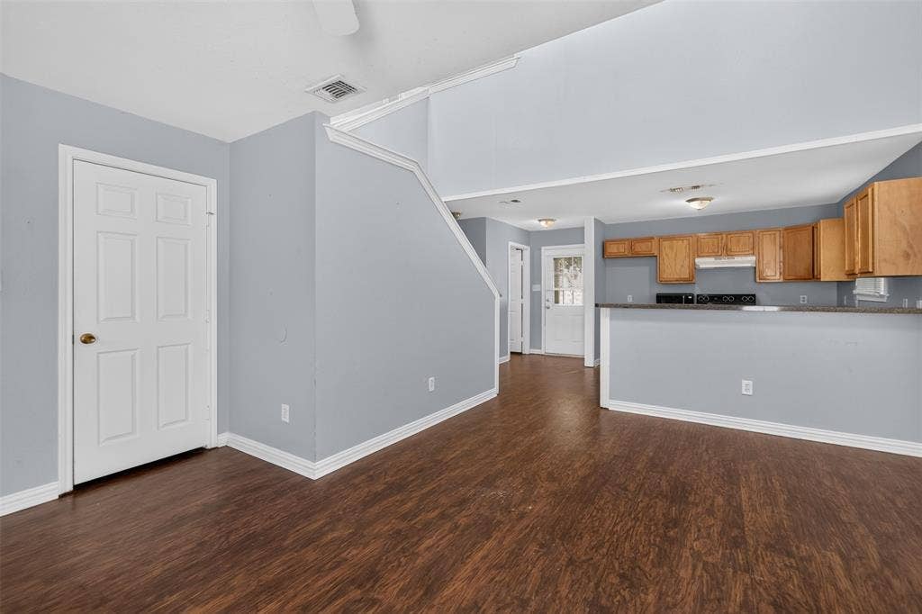1708 Timber View Drive, Tyler, TX 75703 Vaulted ceiling with open mezzanine, wood-finish flooring, and kitchen featuring an extended breakfast bar and wood cabinetry
