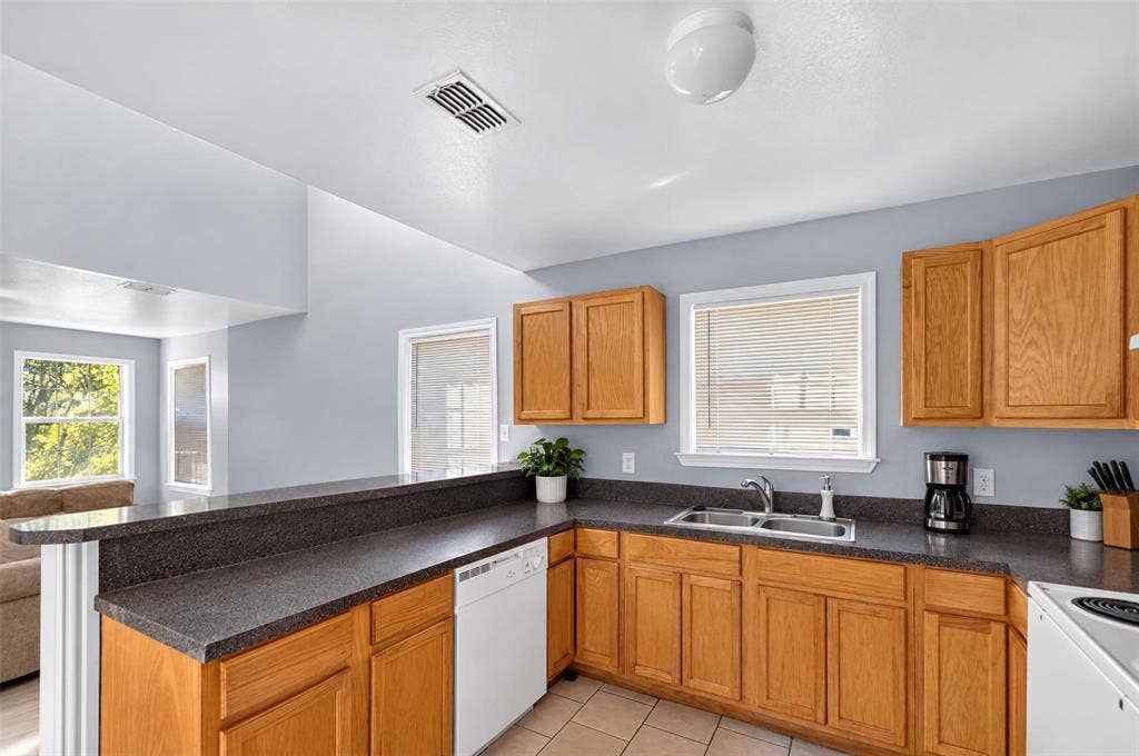 1708 Timber View Drive, Tyler, TX 75703 Kitchen featuring wood cabinetry, dark countertops, a double-basin sink, and tile flooring
