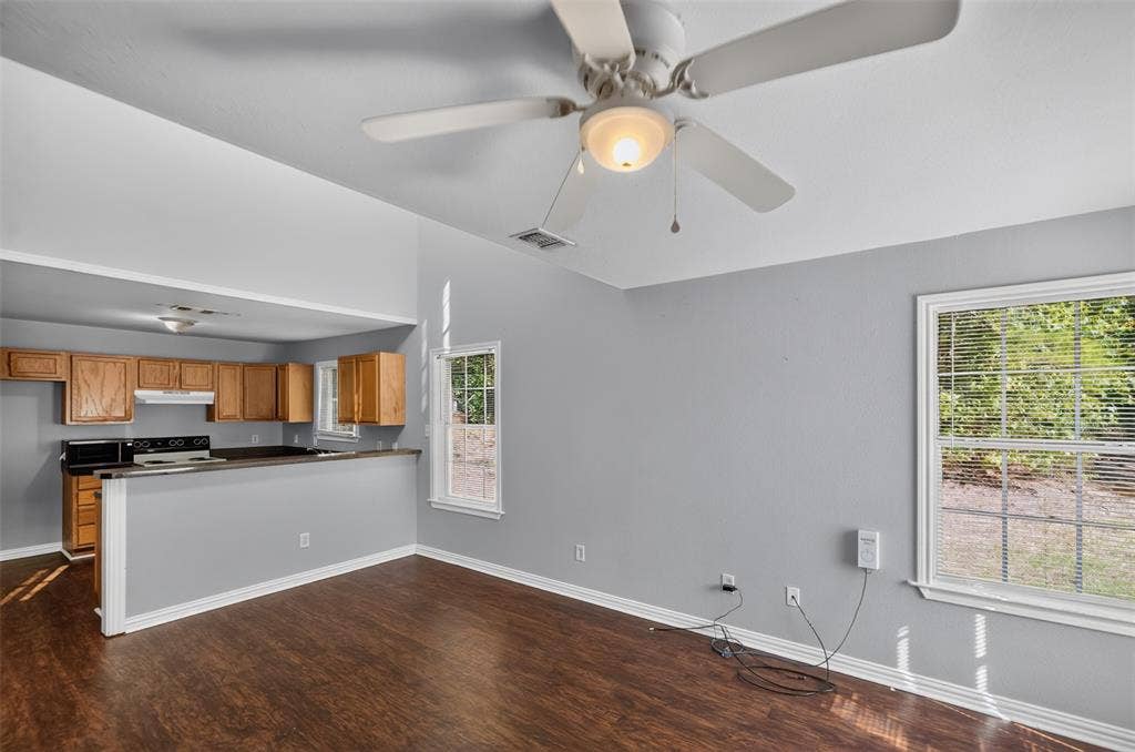 1708 Timber View Drive, Tyler, TX 75703 Vaulted ceiling featuring a central light fixture and ceiling fan, wood-finish flooring, dual-pane windows, and a breakfast bar