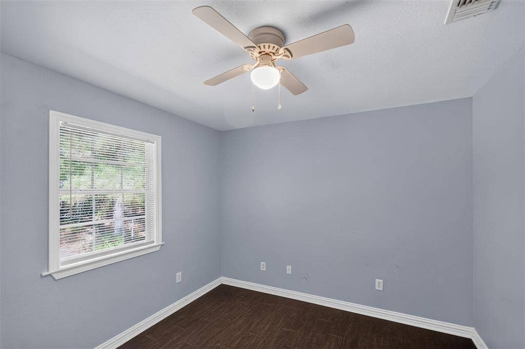1708 Timber View Drive, Tyler, TX 75703 Room featuring wood-finish flooring, a multi-blade ceiling fan with an integrated light fixture, and a window with horizontal blinds