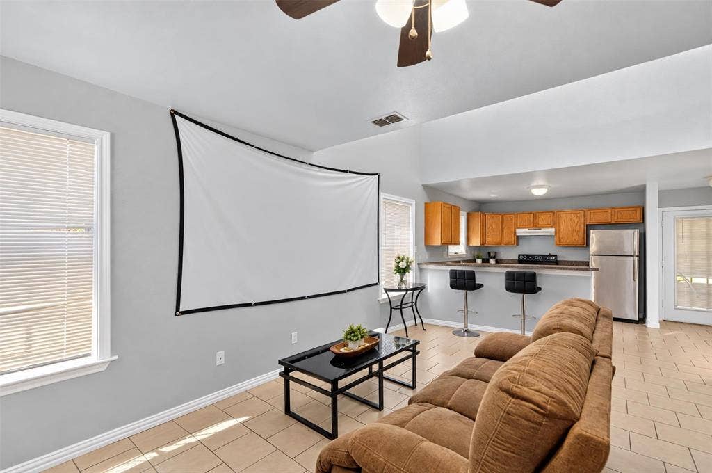 1708 Timber View Drive, Tyler, TX 75703 Vaulted ceilings, ceramic tile flooring, and open-concept layout featuring a kitchen breakfast bar, wood cabinetry, and stainless steel refrigerator