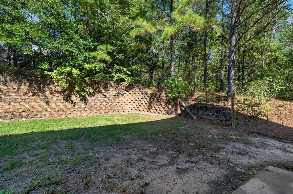 1708 Timber View Drive, Tyler, TX 75703 Backyard featuring a tiered stone retaining wall and mature perimeter trees