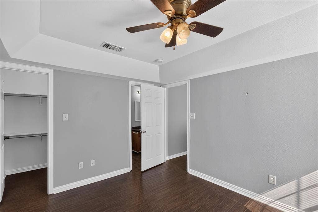 1708 Timber View Drive, Tyler, TX 75703 Tray ceiling with a central multi-light ceiling fan, wood-finish flooring, and a reach-in closet featuring built-in shelving