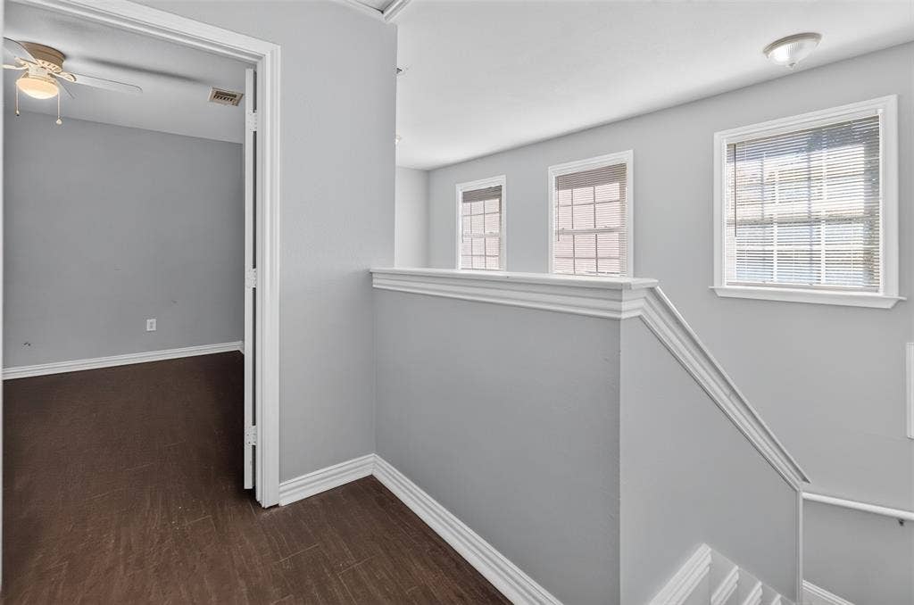 1708 Timber View Drive, Tyler, TX 75703 Neutral-toned interior featuring dark wood-finish flooring, multi-pane windows, decorative chair rail molding, and a ceiling fan with integrated lighting