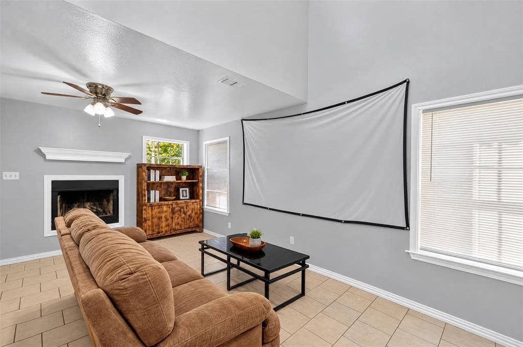 1708 Timber View Drive, Tyler, TX 75703 High-ceiling living space featuring a fireplace with a mantel, built-in shelving, tile flooring, and a ceiling fan
