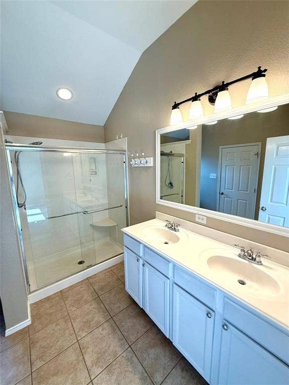 2111 Red River Road, Forney, TX 75126 Bathroom featuring a double-sink vanity with white cabinetry, a glass-enclosed shower, a large wall-mounted mirror, and tile flooring under a vaulted ceiling