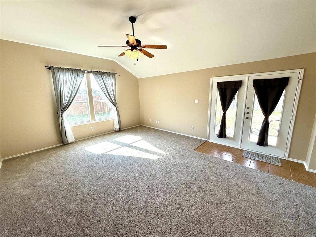 2111 Red River Road, Forney, TX 75126 Vaulted ceilings, carpeted flooring, ceiling fan with light fixture, large windows, and glass-paneled double doors with tiled flooring