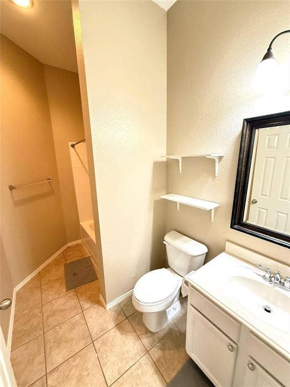 2111 Red River Road, Forney, TX 75126 Bathroom featuring ceramic tile flooring, a white vanity with an integrated sink, dual wall-mounted storage shelves, and a tub-shower combination
