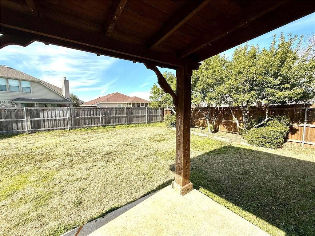2111 Red River Road, Forney, TX 75126 Covered outdoor patio featuring a stained wood support beam, concrete flooring, and a fenced backyard with mature trees