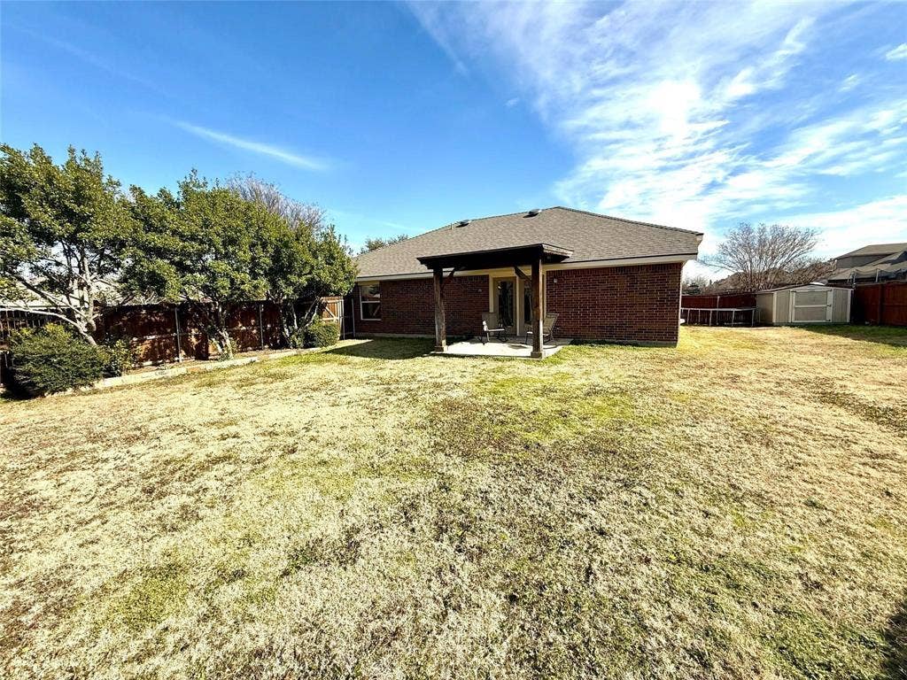 2111 Red River Road, Forney, TX 75126 Brick exterior residence featuring a covered patio, pergola, wood fencing, and mature trees