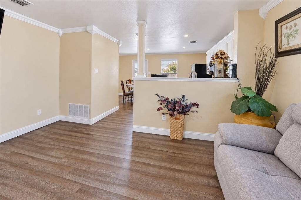 413 Bonnie Court, Anna, TX 75409 Open-concept interior featuring wood-finish flooring, crown molding, a half-wall partition, and a decorative structural column