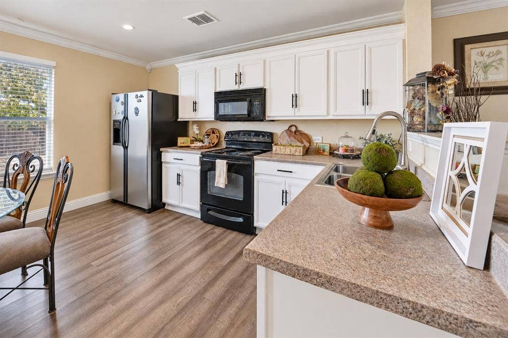 413 Bonnie Court, Anna, TX 75409 Kitchen featuring white shaker-style cabinetry, wood-finish flooring, solid surface countertops, and black built-in appliances