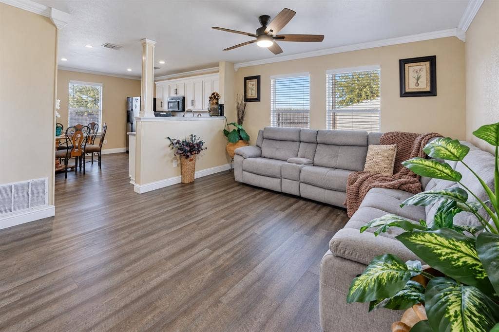 413 Bonnie Court, Anna, TX 75409 Open-concept area featuring wood-finish flooring, crown molding, a ceiling fan with integrated lighting, and a partial partition wall with a column