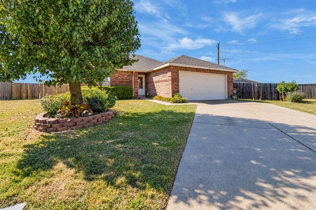 413 Bonnie Court, Anna, TX 75409 Brick exterior residence featuring a front-facing attached garage, concrete driveway, and tiered stone-block landscaping bed