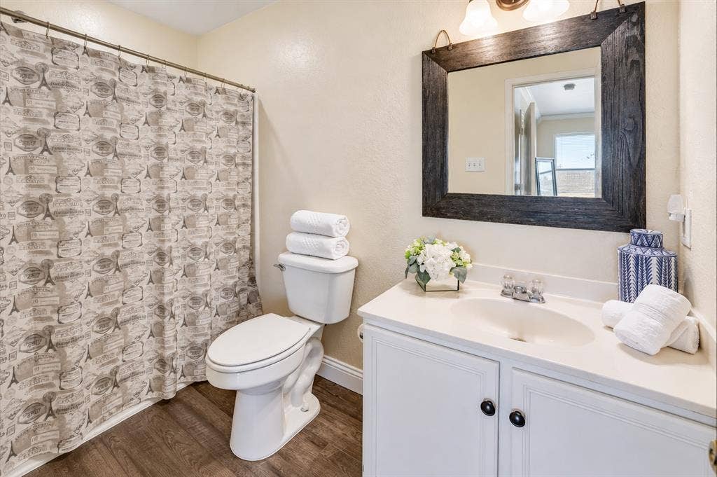 413 Bonnie Court, Anna, TX 75409 Bathroom featuring a white vanity cabinet with an integrated sink, solid surface countertop, dark-toned wood-finish flooring, and a framed mirror with overhead lighting