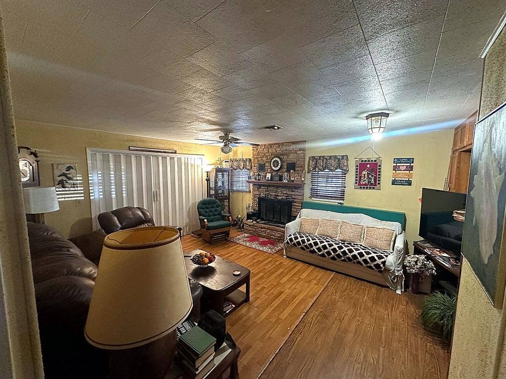 305 McKay Road, Burnet, TX 78611 Living area featuring wood-finish flooring, a floor-to-ceiling brick masonry fireplace with a wood mantel, and a ceiling fan