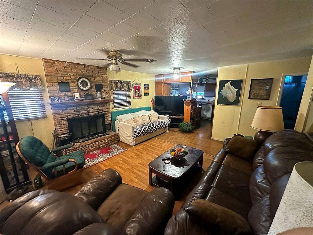 305 McKay Road, Burnet, TX 78611 Floor-to-ceiling stone fireplace with a masonry hearth, wood-finish flooring, and a ceiling fan
