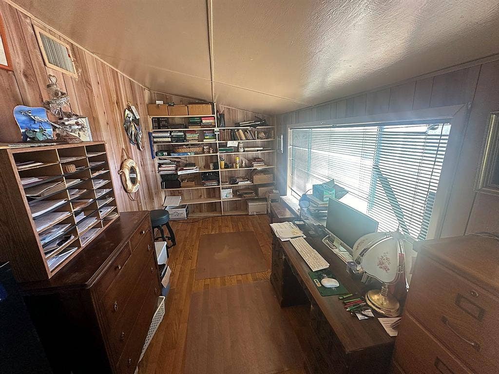 305 McKay Road, Burnet, TX 78611 Wood-paneled walls, built-in shelving units, wide horizontal window with blinds, and wood-finish flooring