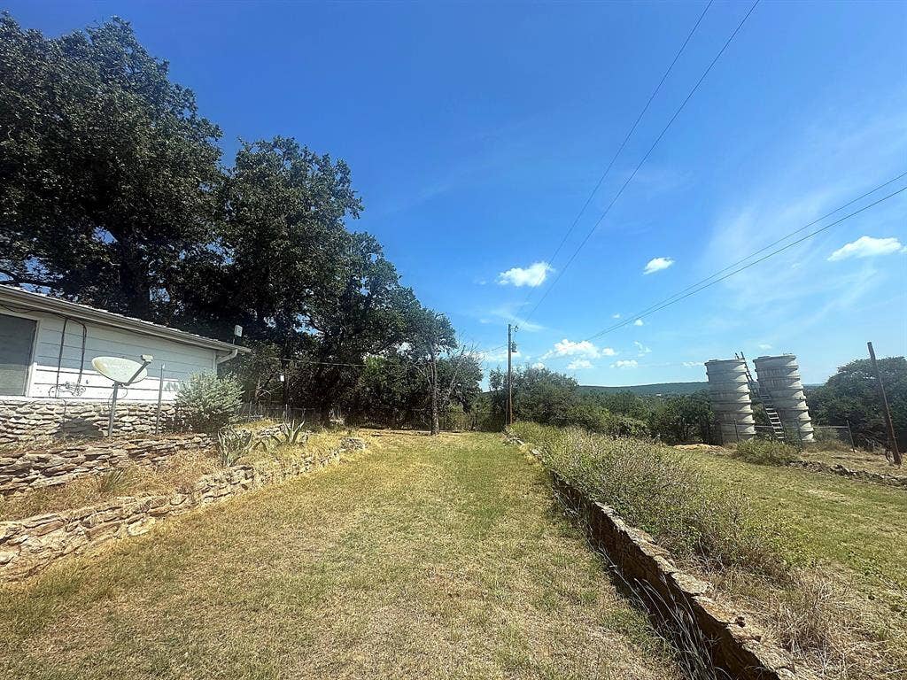 305 McKay Road, Burnet, TX 78611 Expansive grounds featuring natural stone retaining walls, mature oak trees, and industrial storage silos