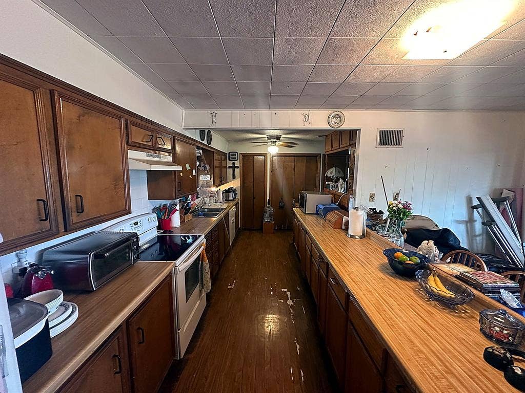 305 McKay Road, Burnet, TX 78611 Galley kitchen featuring wood cabinetry, laminate countertops, integrated range, and wood-finish flooring