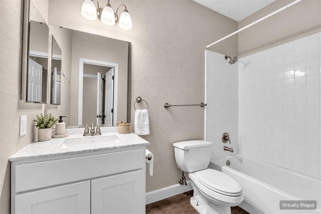 2410 S 2nd Street, #625, Waco, TX 76706 White shaker-style vanity with a stone-finish countertop, undermount sink, three-light vanity fixture, and a white tiled shower surround
