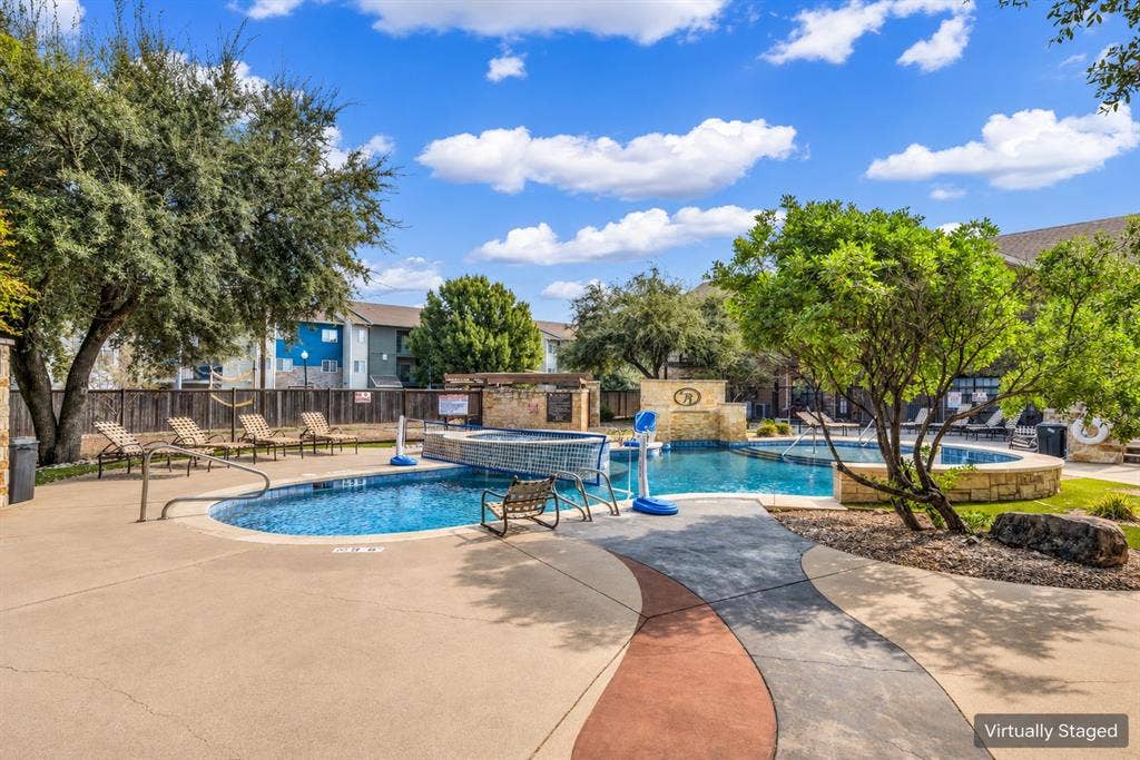 2410 S 2nd Street, #625, Waco, TX 76706 In-ground pool featuring a stone water feature, attached spa, concrete decking, and perimeter privacy fencing