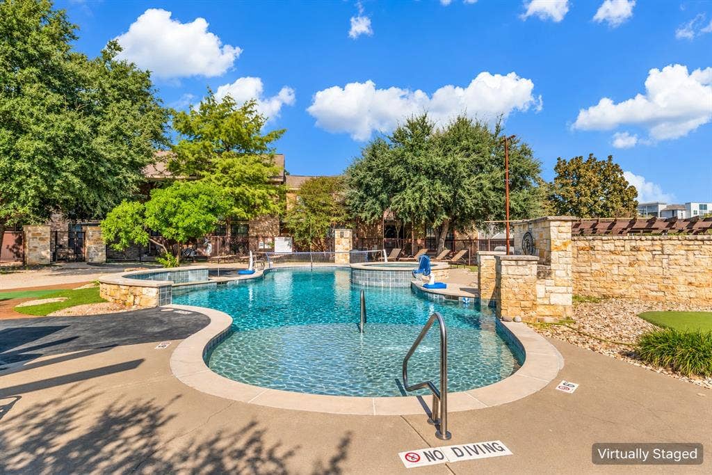 2410 S 2nd Street, #625, Waco, TX 76706 Swimming pool featuring stone-accented perimeter walls, a raised spa, tanning ledge with metal handrails, and surrounding concrete decking