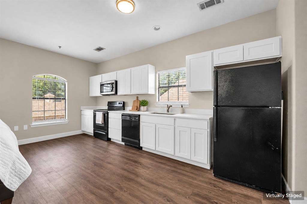 2410 S 2nd Street, #625, Waco, TX 76706 Kitchen featuring white cabinetry, solid-surface countertops, black appliances, and wood-finish flooring